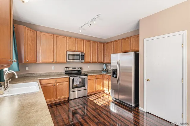 a kitchen with granite countertop stainless steel appliances a sink refrigerator stove and microwave