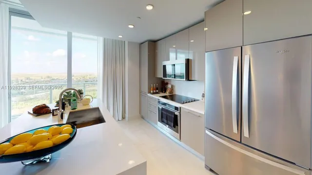 a kitchen with stainless steel appliances granite countertop a refrigerator a stove and a wooden floors