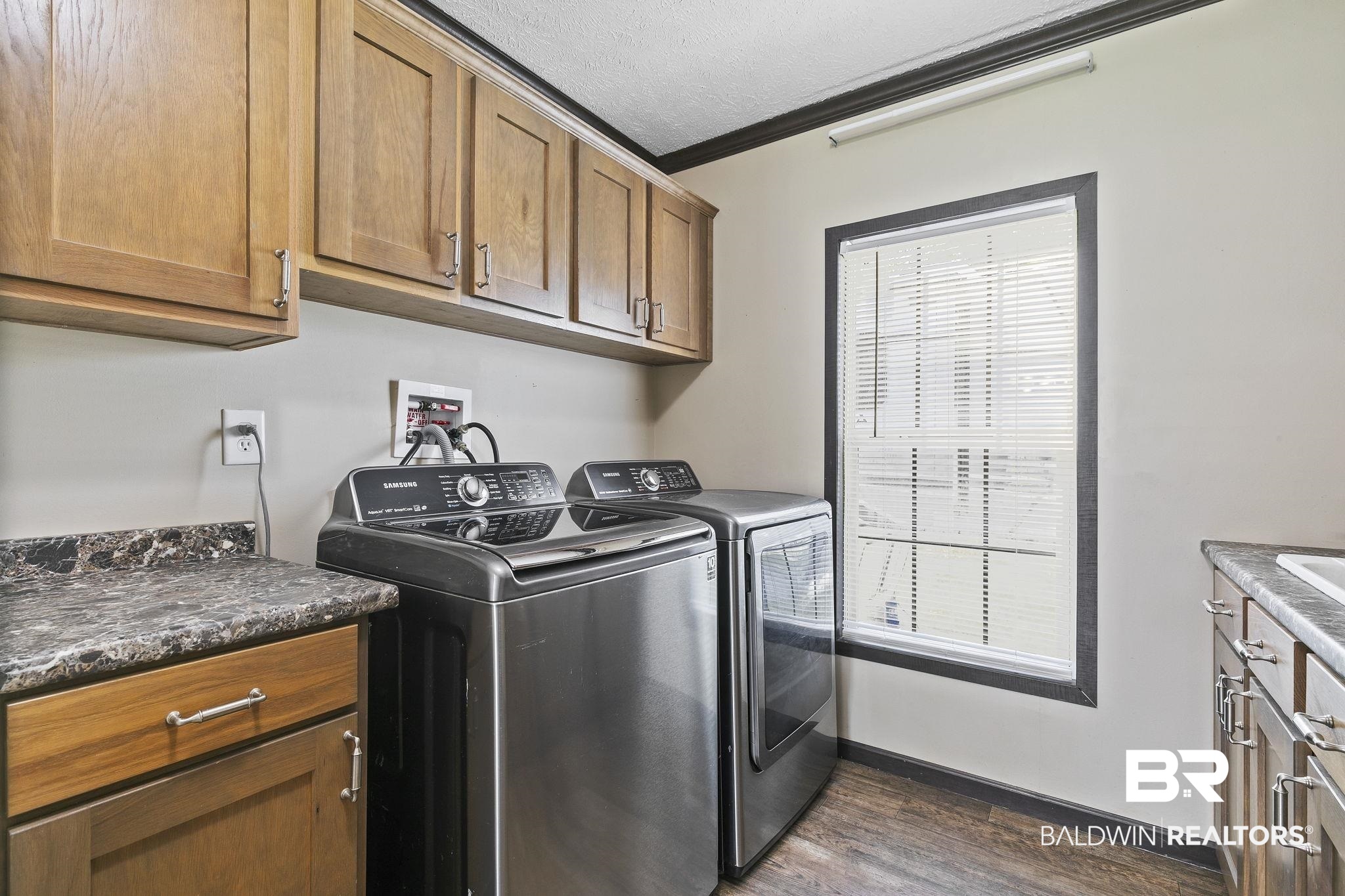 35641 County Road 39 Stapleton, AL 36578 - Photo 20 of 46 Laundry area with independent washer and dryer, a textured ceiling, crown molding, cabinets, and dark hardwood / wood-style floors
