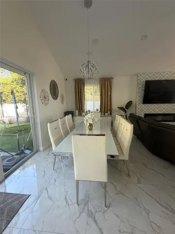 a living room with furniture a flat screen tv and a floor to ceiling window