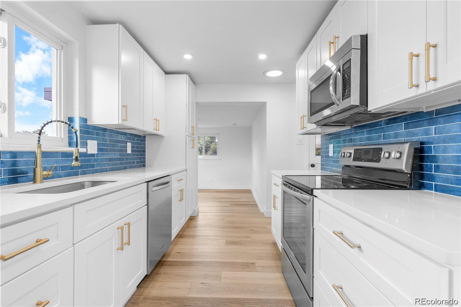 6500 West 32nd Avenue Wheat Ridge, CO 80033 - Photo 9 of 39 a kitchen with stainless steel appliances granite countertop a sink and dishwasher a stove top oven with wooden floor