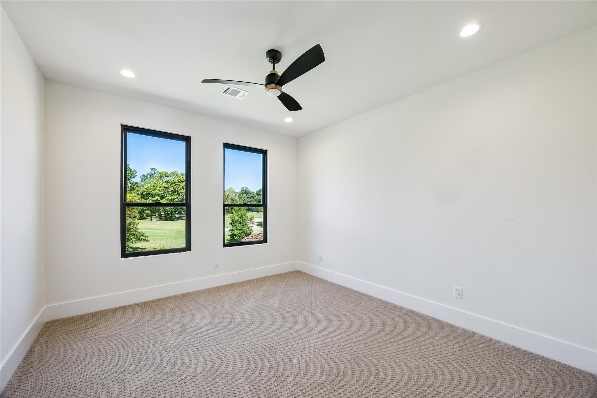 65 Shadow Creek Ridge Drive Spring, TX 77389 - Photo 34 of 41 Bright upstairs secondary bedroom with oversized windows, recessed lighting, and ceiling fan overlooking serene golf course views.
