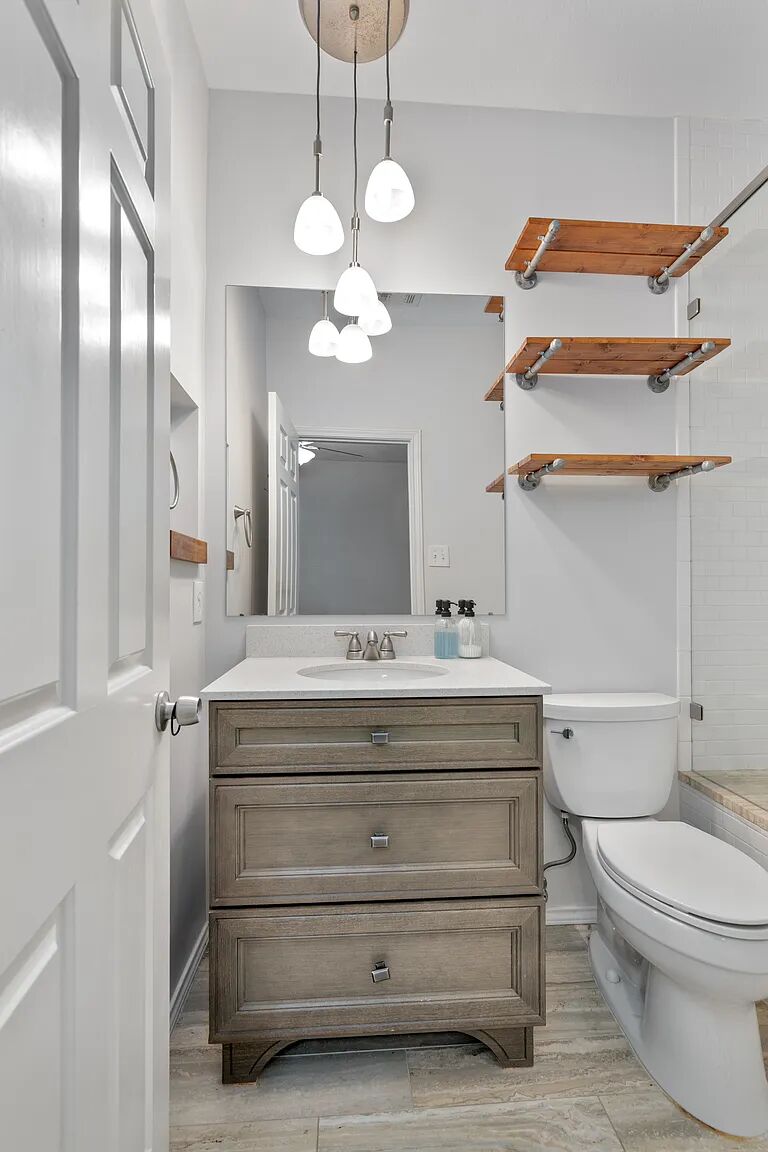 11970 Jollyville Road, Unit 202 Austin, TX 78759 - Photo 14 of 25 A well-lit bathroom features a modern vanity, spacious mirror, and open shelving.