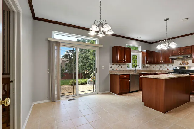 a open kitchen with a refrigerator a stove top oven a sink with a dining table and chairs