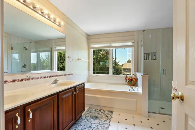 a bathroom with a tub a sink and a large mirror next to a window