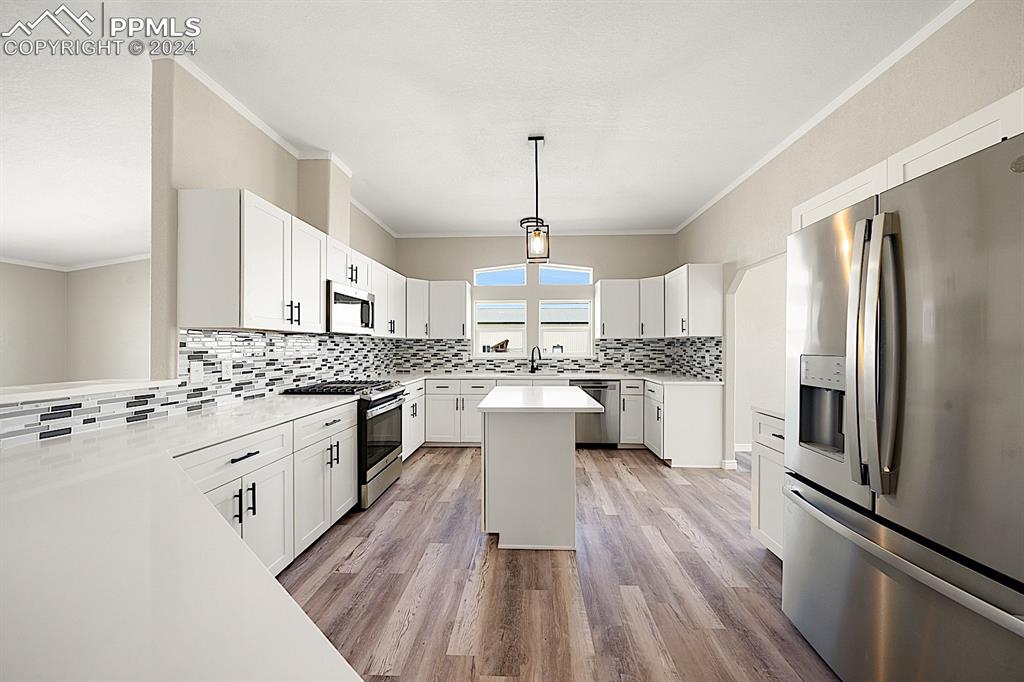8160 Edison Road Yoder, CO 80864 - Photo 19 of 42 a kitchen with a refrigerator a sink dishwasher a stove and white cabinets with wooden floor