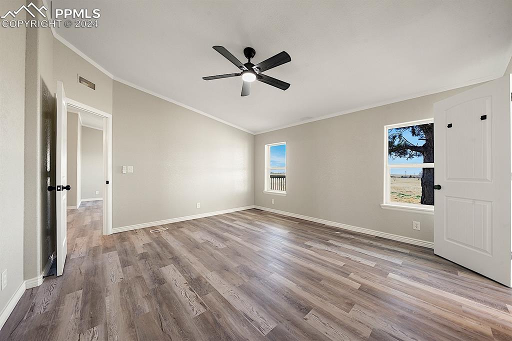 8160 Edison Road Yoder, CO 80864 - Photo 21 of 42 an empty room with wooden floor a ceiling fan and windows