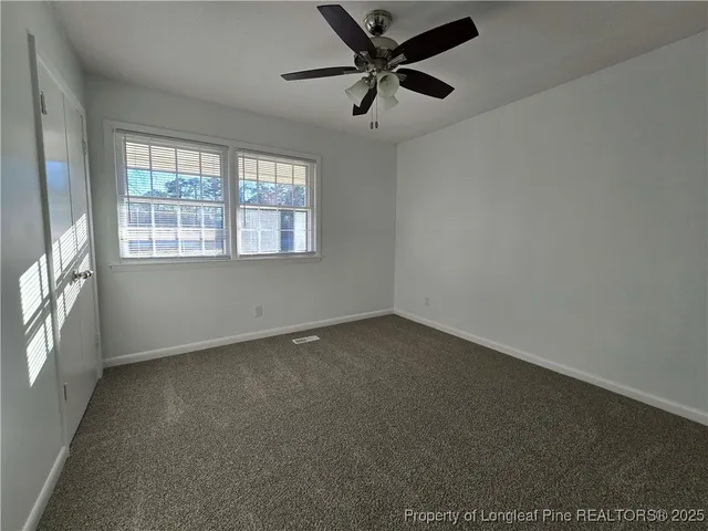 an empty room with a window and a fan