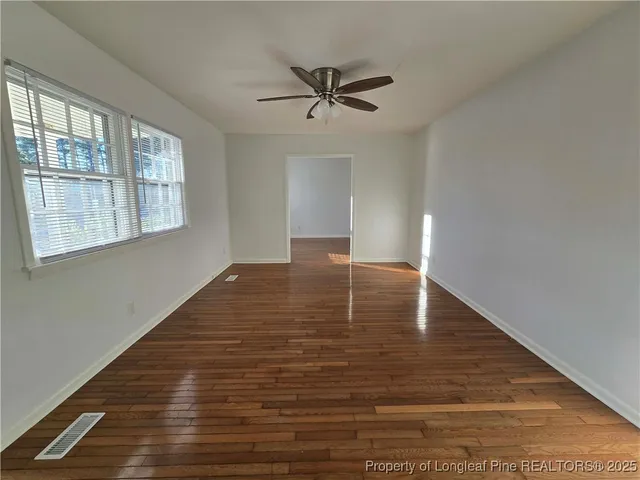 a view of empty room with wooden floor and fan