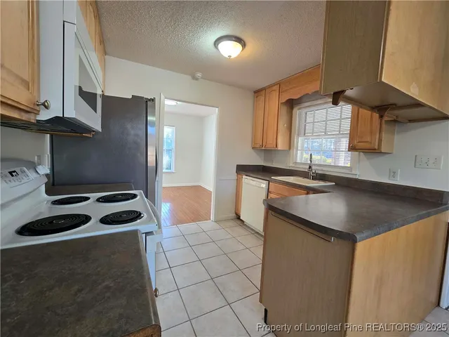 a kitchen with granite countertop a sink a stove and a refrigerator