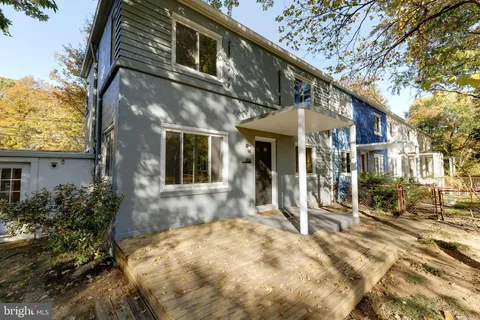a view of a white house with large windows and a table and chairs