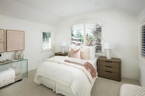 a bedroom with a bed a lamp and a large window