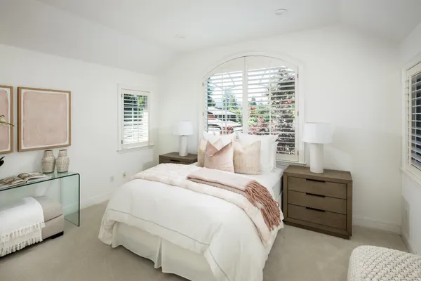 a bedroom with a bed a lamp and a large window