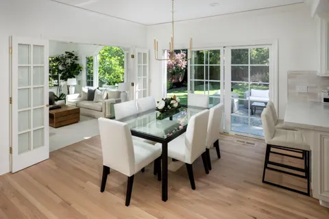 a dining room with furniture large windows and wooden floor
