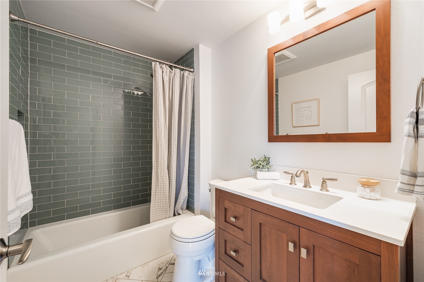 548 North 75th Street Seattle, WA 98103 - Photo 27 of 39 a bathroom with a sink a toilet a mirror a bathtub and shower