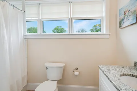 a bathroom with a granite countertop toilet and a sink