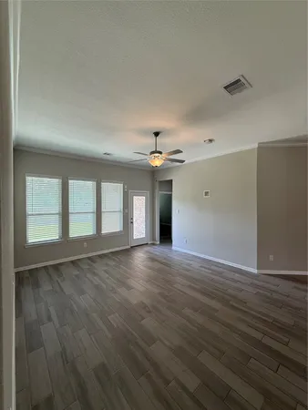 a view of an empty room with window and wooden floor