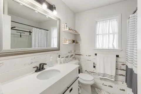 a bathroom with a sink toilet mirror and tub