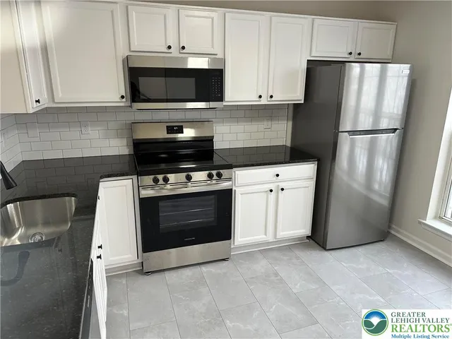a kitchen with white cabinets appliances and sink