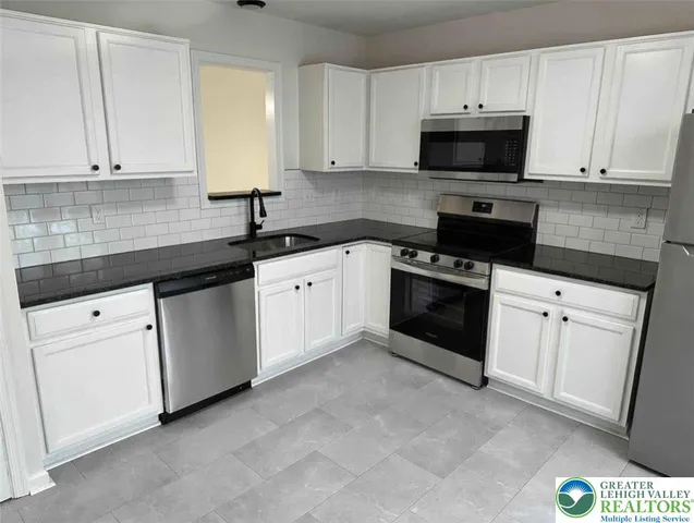 a kitchen with granite countertop white cabinets and white appliances