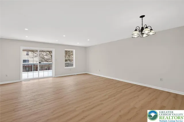 a view of an empty room with window and wooden floor