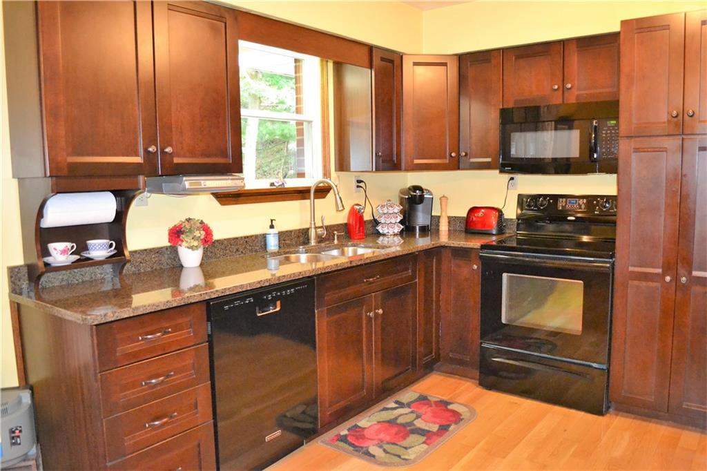 119 Pine Tree Road Kittanning, PA 16201 - Photo 13 of 25 Close up view of the granite countertops, cherry cabinets, and black appliances.