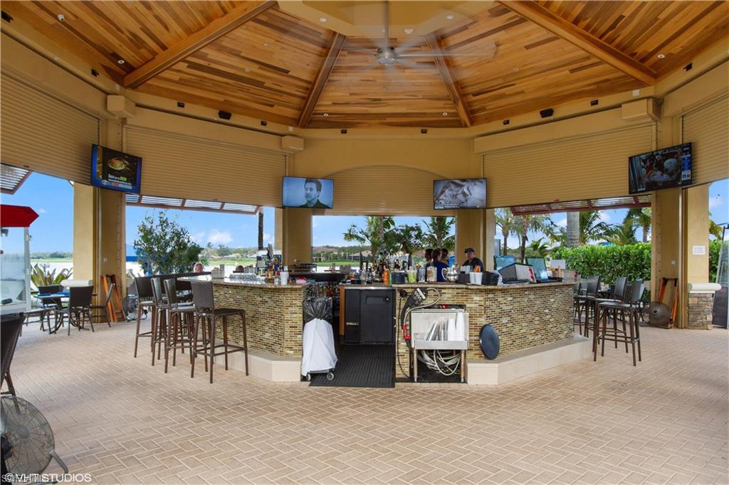9293 Quarry Drive Naples, FL 34120 - Photo 27 of 28 a view of a patio with dining table and chairs under an umbrella