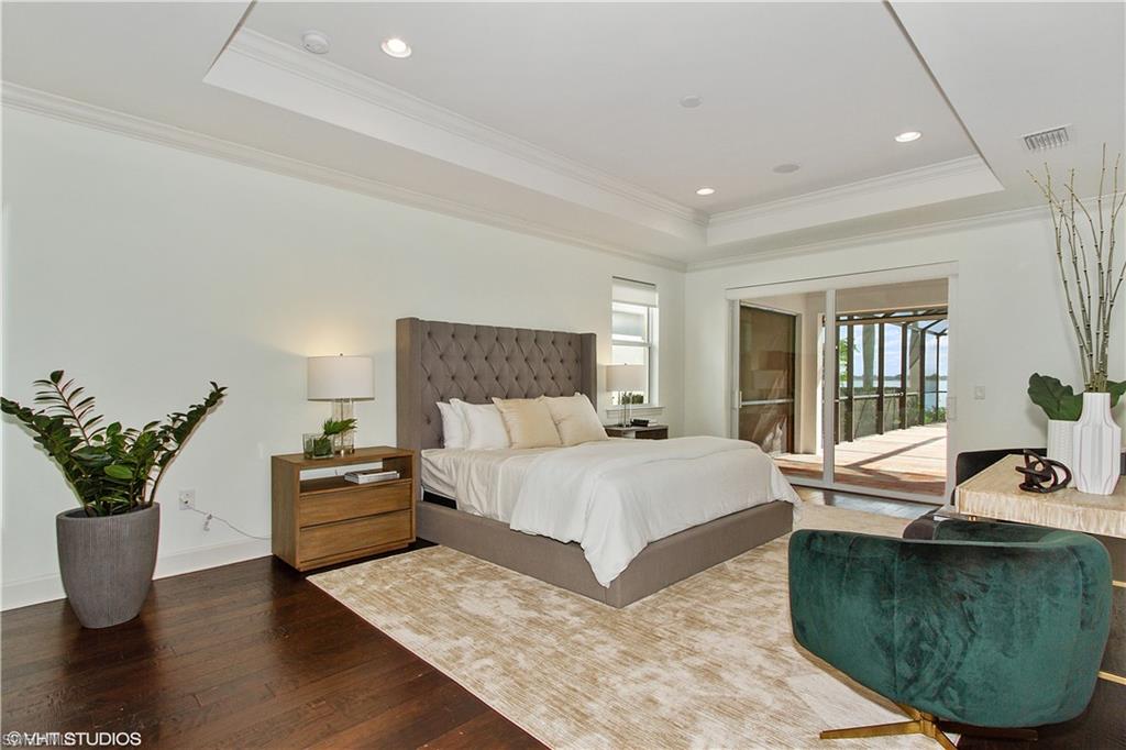 9293 Quarry Drive Naples, FL 34120 - Photo 7 of 28 a bedroom with a large bed and wooden floor