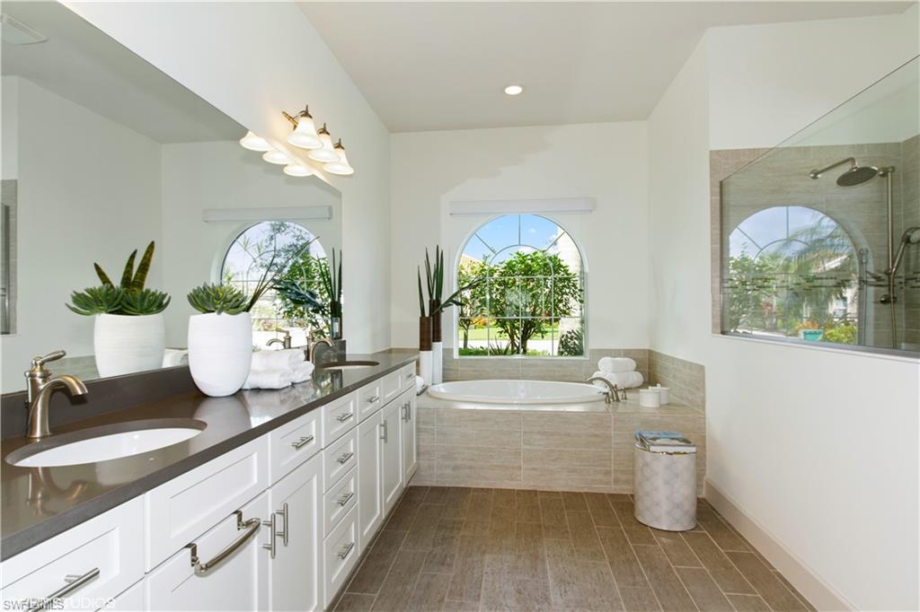 9293 Quarry Drive Naples, FL 34120 - Photo 8 of 28 a bathroom with a granite countertop double vanity sink a mirror and a bathtub