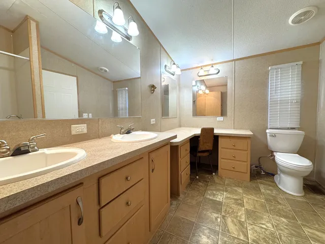 a spacious bathroom with a double vanity sink toilet mirror and bathtub