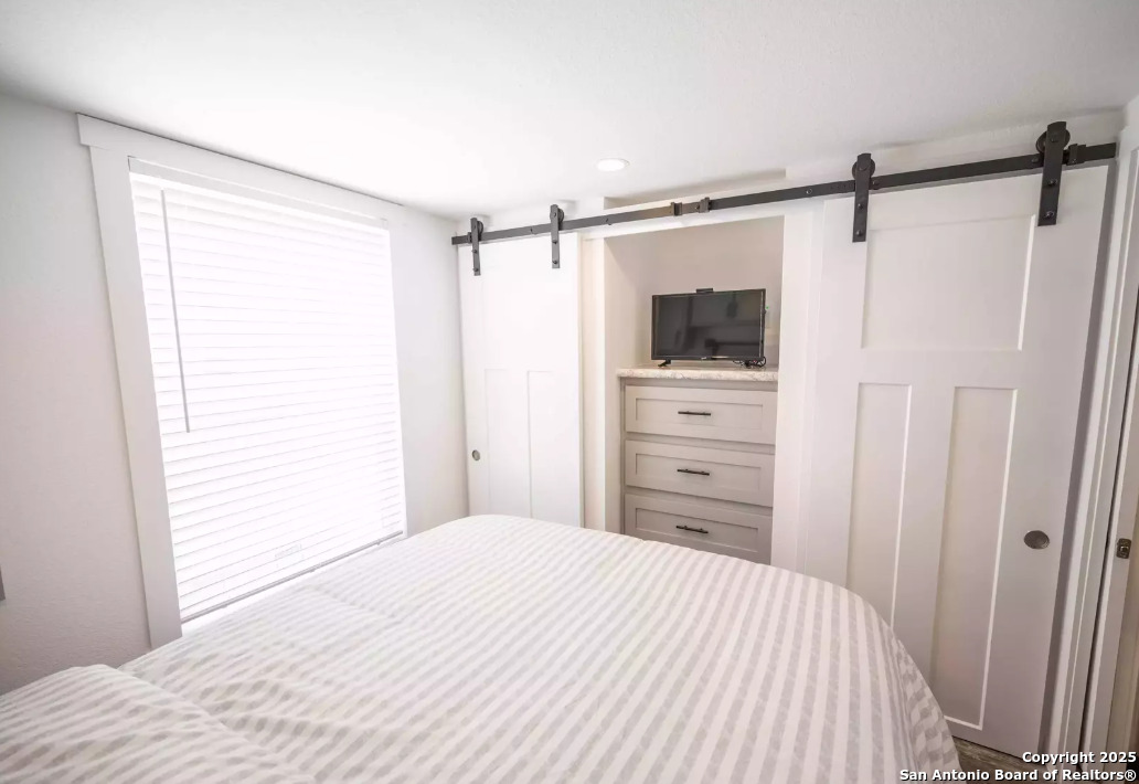 5386 Ranch Road 1376, Unit 114 Fredericksburg, TX 78624 - Photo 13 of 29 a bedroom with a bed and a flat tv screen