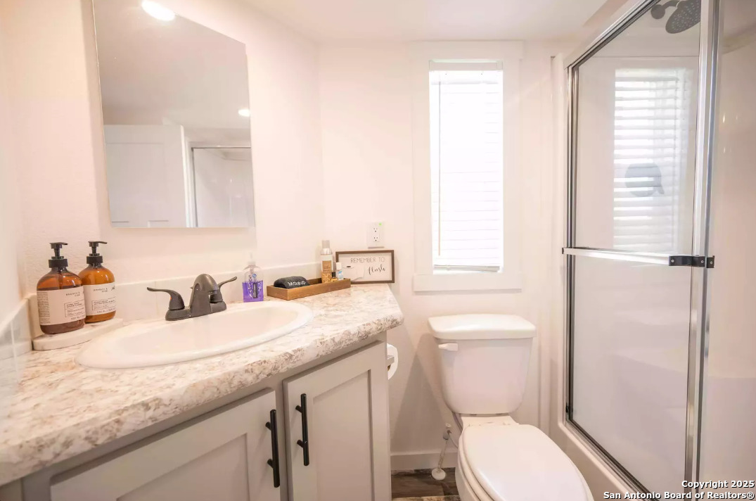 5386 Ranch Road 1376, Unit 114 Fredericksburg, TX 78624 - Photo 14 of 29 a bathroom with a granite countertop toilet sink and a mirror
