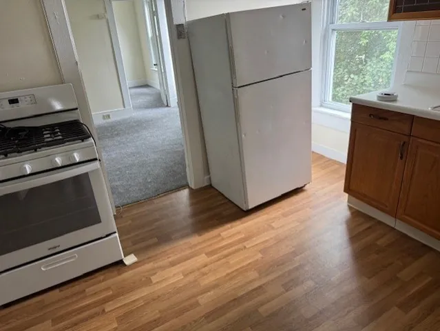 a kitchen with a refrigerator stove and wooden floor