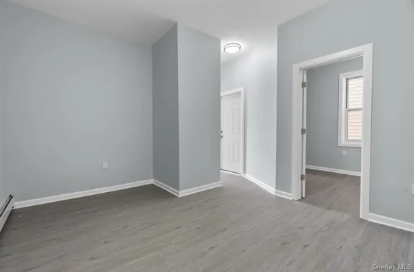 an empty room with wooden floor & windows