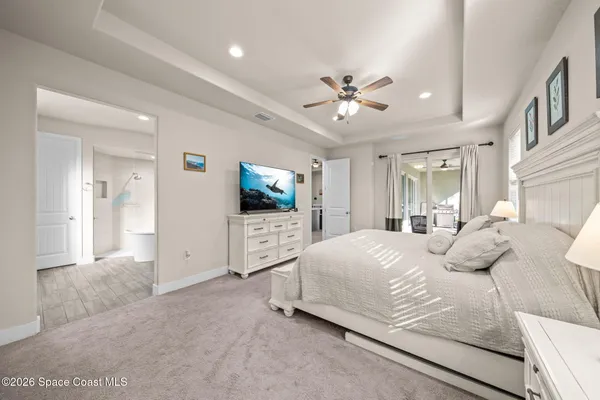 a bedroom with a large bed a flat tv screen and a dresser