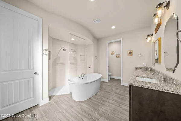 a spacious bathroom with a double vanity sink mirror and bathtub