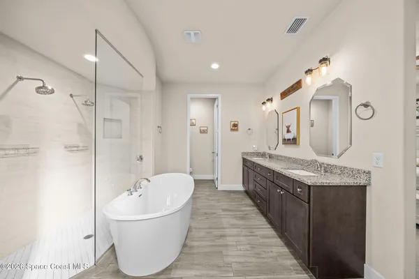 a spacious bathroom with a tub sink and mirror