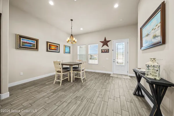 a dining room with wooden floor a chandelier a wooden table and chairs
