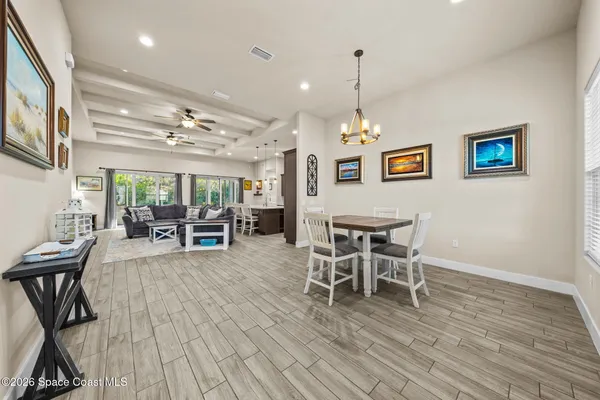 a dining room with wooden floor a chandelier a wooden table and chairs