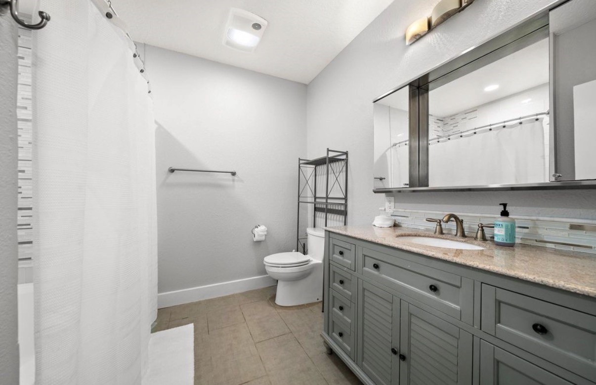 1633 Castle Court Houston, TX 77006 - Photo 12 of 38 **Staged bathroom featuring a beautifully updated vanity, modern fixtures, and a clean, neutral palette. The bright lighting and spacious countertop highlight the room’s functionality, while the staged décor showcases how easily the space can feel both stylish and inviting.**