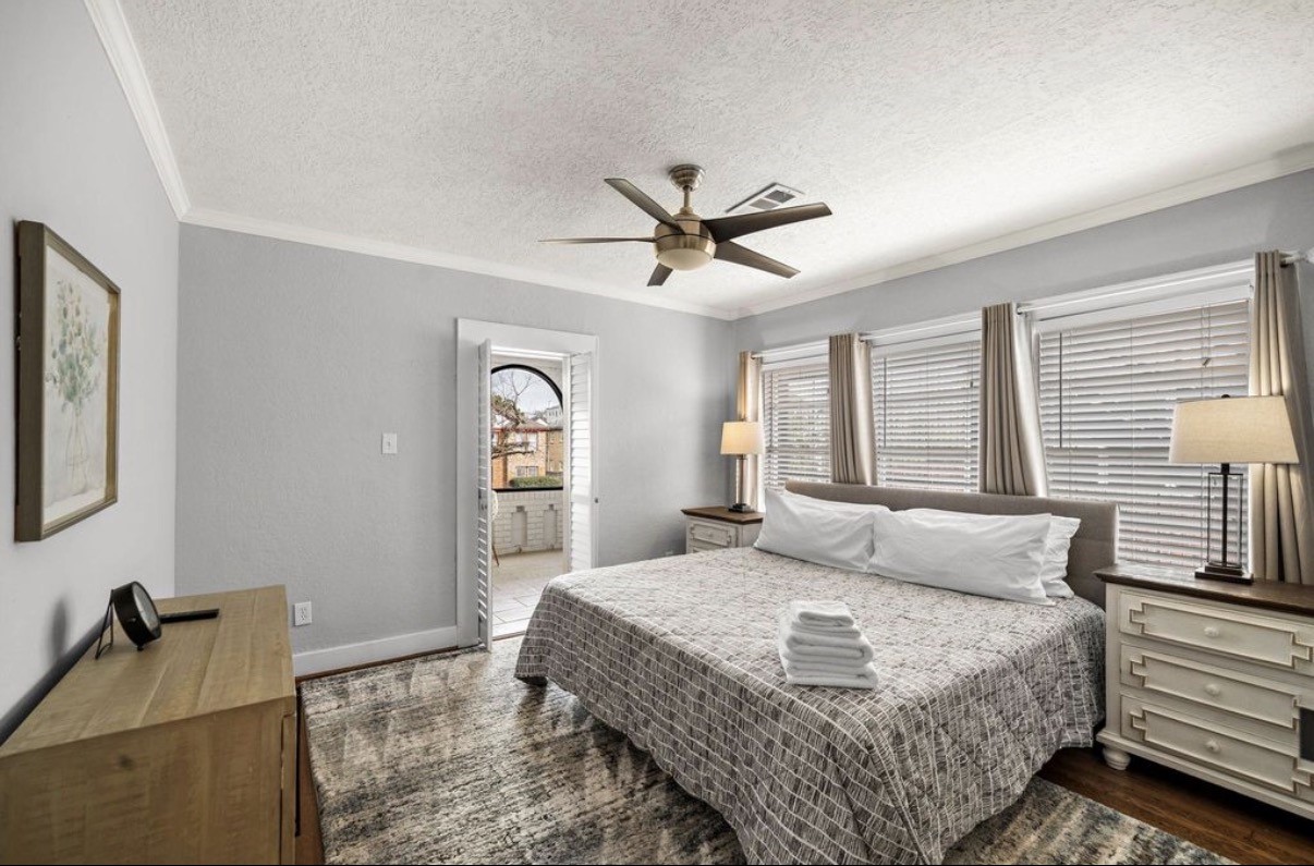 1633 Castle Court Houston, TX 77006 - Photo 16 of 38 Spacious, beautifully staged bedroom featuring abundant natural light, warm hardwood floors, and a serene color palette. The room offers ample space for a king-size bed, stylish furnishings, and comfortable everyday living, creating a relaxing retreat within the home.