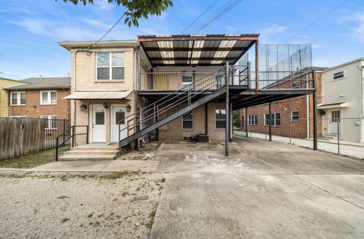 1633 Castle Court Houston, TX 77006 - Photo 18 of 38 Expanded rear structure with private entrances for each unit, plus a spacious parking area offering ample room for multiple vehicles. The upper unit features an exterior staircase leading to a large covered deck, perfect for outdoor seating or storage. Secure, low-maintenance, and conveniently designed for comfortable duplex living.
