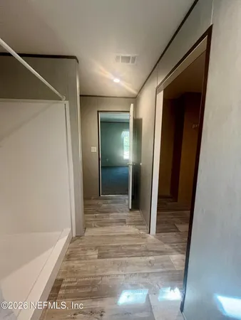 a view of a hallway with wooden floor and a bathroom