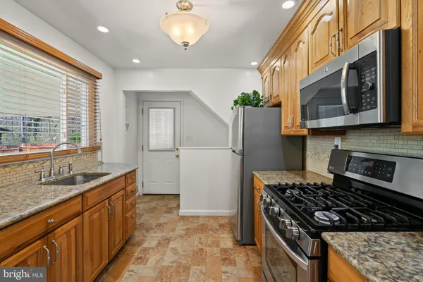 a kitchen with stainless steel appliances granite countertop a sink stove and refrigerator