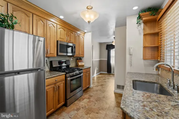 a kitchen with granite countertop a refrigerator stove and sink