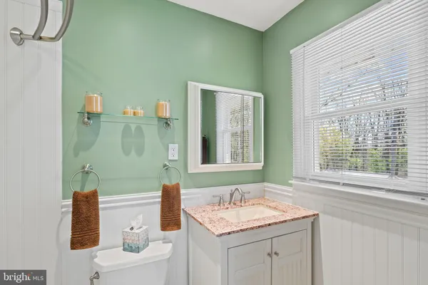 a bathroom with a sink vanity granite toilet tub and next to a window
