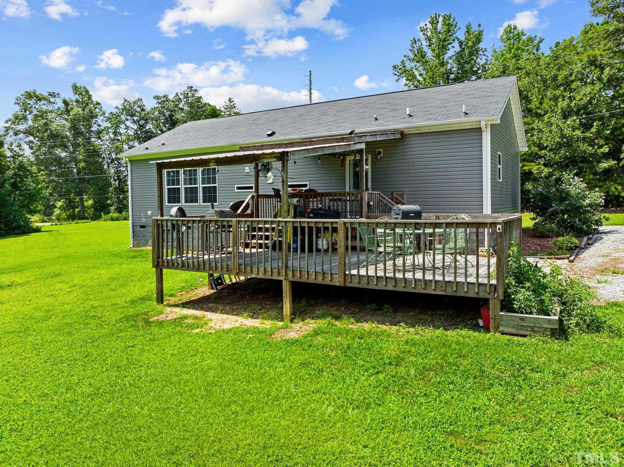 1467 Nelson Loop Roxboro, NC 27574 - Photo 12 of 32 a view of a house with a backyard and a wooden deck