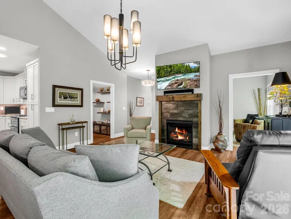 a living room with furniture a fireplace and a chandelier