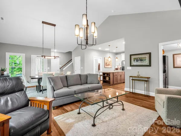 a living room with furniture kitchen view and a chandelier