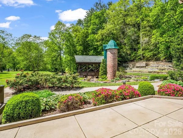 a front view of a house with a yard and fountain in middle of green field